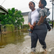 A woman carries a child through a flooded street in New Orleans on Wednesday, July 10, 2019.